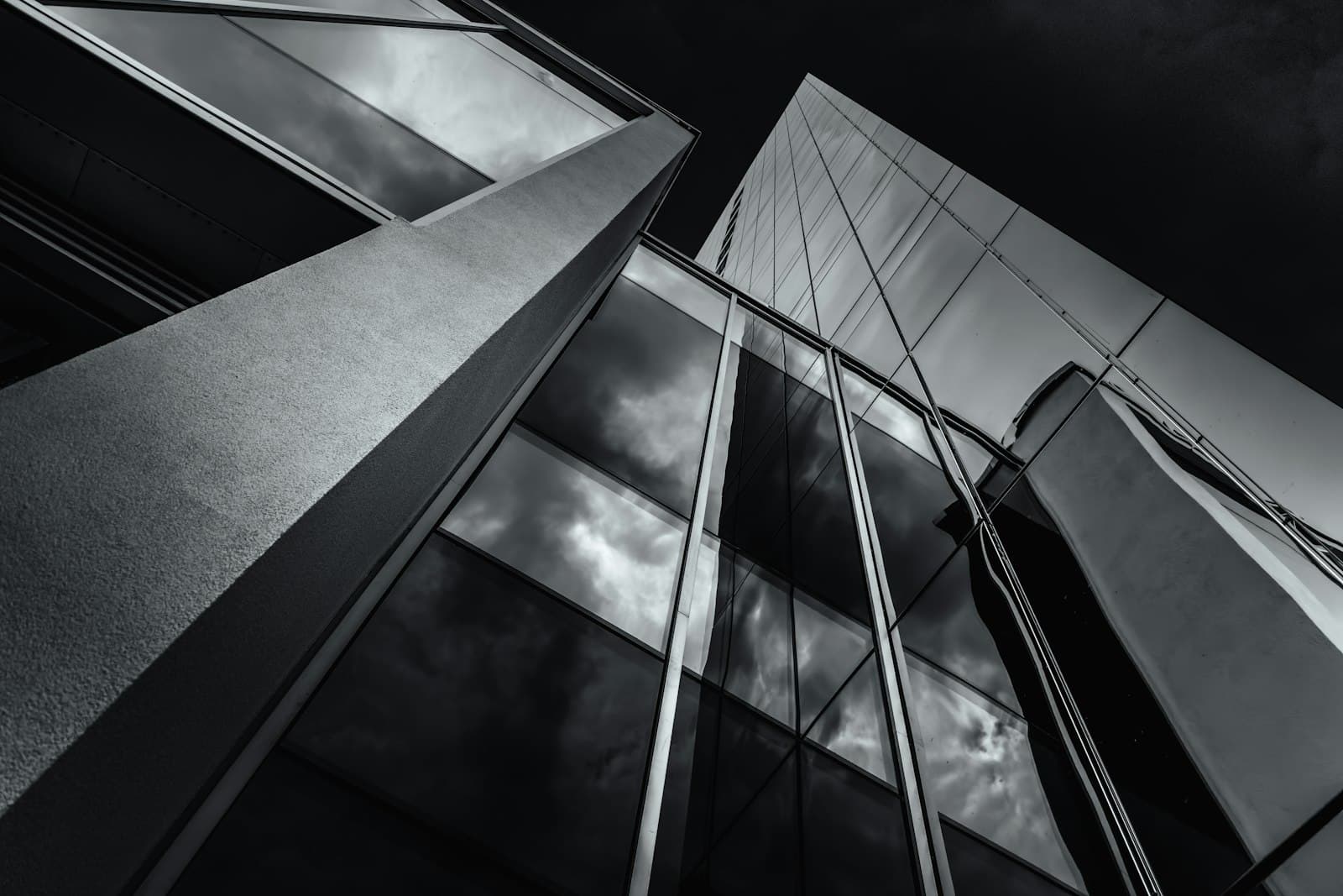 Angled glass and steel facade seen from below, in black and white